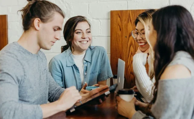 Group of young people having a discussion around a laptop