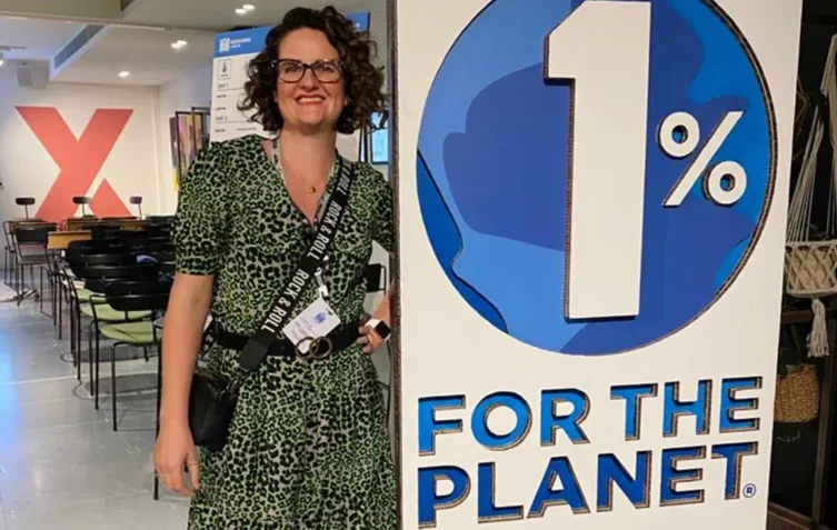 Lynne standing next to a a large "1% For the Planet" sign